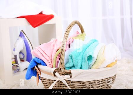 Asciugamani colorati in cesto su sfondo interno casa Foto Stock