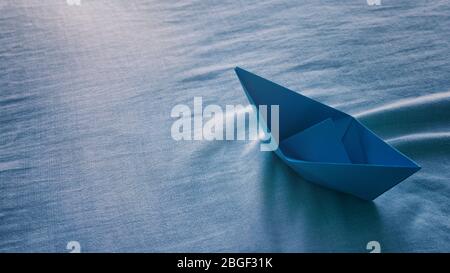 Blu carta origami barca vela sole Coast.Creativity arte origami barca sedersi su lenzuola sembra vela e fare onde Foto Stock