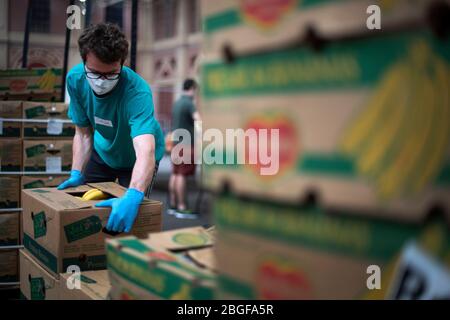 I volontari del progetto alimentare Edible London aiutano a preparare scatole di banane pronte per le parcelle alimentari presso Alexandra Palace di Londra, che è stata trasformata in un centro di distribuzione alimentare per aiutare coloro che sono in necessità durante l'epidemia di coronavirus. Foto Stock