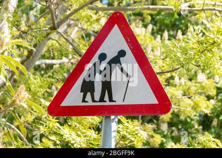 Una vista ravvicinata di una persona anziana che attraversa la strada o un cartello stradale per avvisare i conducenti Foto Stock