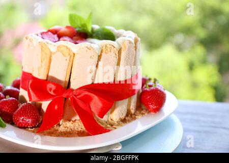 Torta gustosa Charlotte con fragole fresche su sfondo verde natura Foto Stock