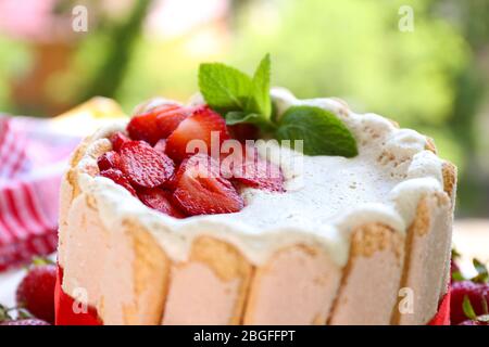 Torta gustosa Charlotte con fragole fresche su sfondo verde natura Foto Stock