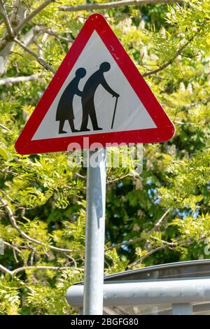Una vista ravvicinata di una persona anziana che attraversa la strada o un cartello stradale per avvisare i conducenti Foto Stock
