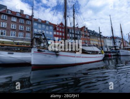 Nyhavn, Copenaghen - Giugno 2019: Disfocused case colorate con barche bianche in primo piano. Foto Stock