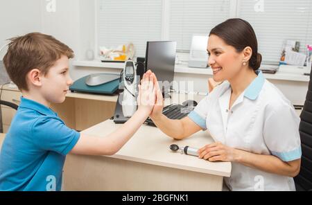 Pediatra che ha cinque con ragazzo positivo dopo il trattamento uditivo. Clinica uditiva. Trattamento sordità Foto Stock