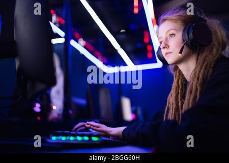 Streamer bella ragazza professionale sorriso giocatore giocare giochi online computer con cuffie, colore neon Foto Stock