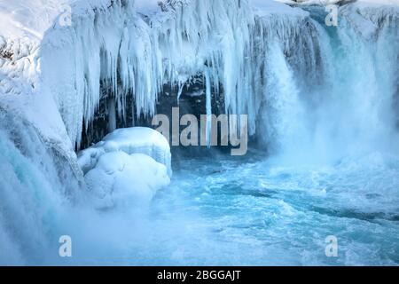 Il fiume islandese ghiacciato a metà Skjalfandafljot scorre sulla cascata Godafoss in inverno. Ancora in forte scorrimento ma neve coperta e con grande icic Foto Stock