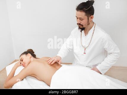 Il chiropratico dà la sua energia al paziente. medico che fa un massaggio energetico alla donna Foto Stock