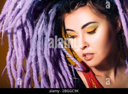 donna ritratto con lucchetti viola e trucco colorato. Stile, acconciature e trucco Foto Stock