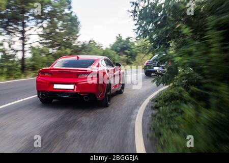 Auto sportive rosse e nere che si passano in paesaggi Foto Stock