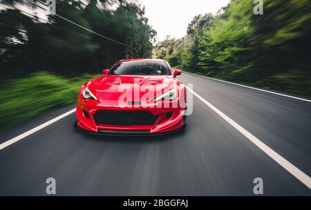 Superpotenza auto da corsa rossa sul paesaggio in marcia, vista sfocata Foto Stock
