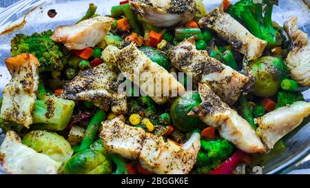 Pesce sano al forno con verdure, filetto di merluzzo fritto con lattuga e verdure da vicino, fuoco selettivo, spezie cavoli di bruxelles, vegetariano Foto Stock