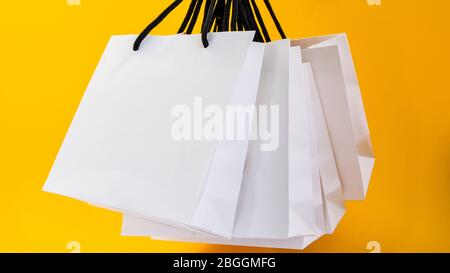 Set di sacchetti di carta bianca per lo shopping su sfondo giallo. Mockup per il design Foto Stock