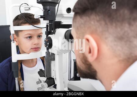 L'optometrista esamina il ragazzo di un paziente con speciali attrezzature oftalmiche in una clinica moderna. Correzione della vista nei bambini Foto Stock