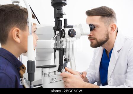 Un medico esperto controlla la vista di un ragazzo adolescente. Clinica moderna per il controllo e il trattamento della vista Foto Stock