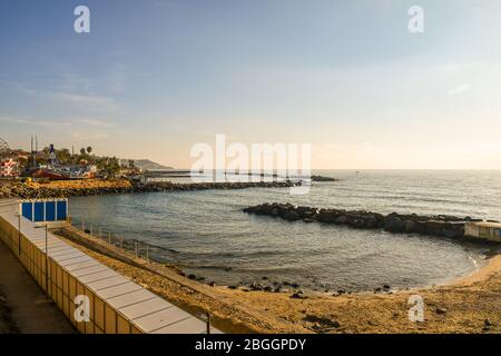 Vista su una spiaggia vuota con una fila di cabine, frangiflutti rocciosi e la costa sullo sfondo, Sanremo, Imperia, Liguria, Italia Foto Stock