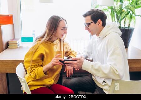 Il ragazzo e la ragazza guardano lo smartphone e comunicano. Foto Stock