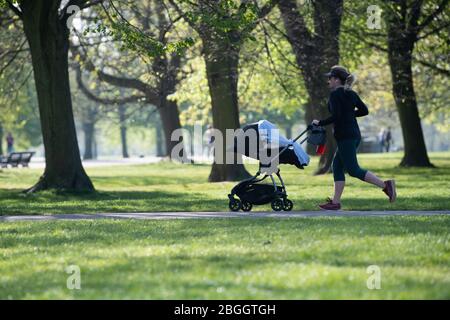 Donna che corre con un passeggino a Kensington Gardens durante il Lockdown a Londra nel Regno Unito, dove è consentito un esercizio all'aperto al giorno. Foto Stock