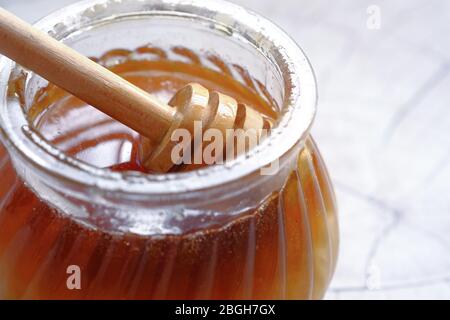 cucchiaio in un vaso di vetro di miele su sfondo bianco. Foto Stock