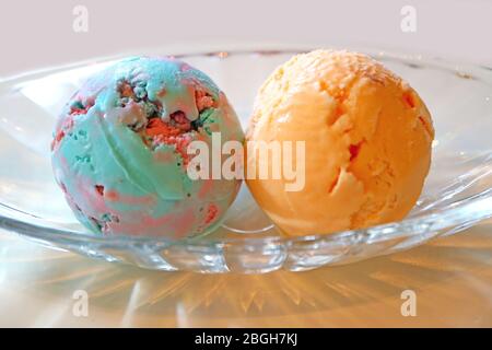 Due cucchiai di gelato alla Bubble Gum e gelato all'arancia in una ciotola di vetro Foto Stock