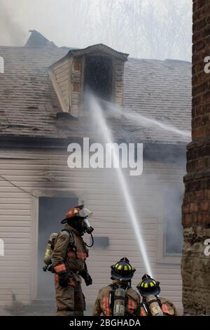 Vigili del fuoco indossare indumenti protettivi fuoco casa battaglia. 911 emergenza contenente incendio da propagazione. Foto Stock