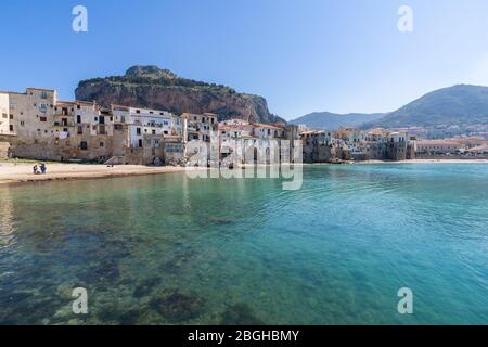 Idilliaca vista sul mare turchese e le case con Rocca di Cefalu montagna rocciosa sullo sfondo visto dal vecchio porto storico di Cefalu - Sicilia, Italia Foto Stock