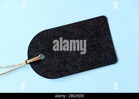 Etichetta regalo nera arrotondata vuota con spago di iuta naturale. Etichetta di cartone Kraft su fondo azzurro con spazio per la copia. Foto Stock