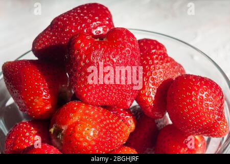 Fragole in una ciotola di vetro. Frutta aromatica. Dessert sano. Sfondo luminoso. Foto Stock