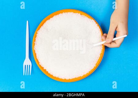 Un bambino mangia i pellets di plastica da un plate.concept di inquinamento ambientale con la plastica Foto Stock