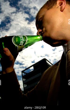 Un uomo di Perrier di bere acqua in bottiglia. Foto Stock