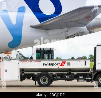 CARDIFF, GALLES - GIUGNO 2019: Autocarro per la fornitura di acqua per aeromobili che serve sotto la coda di un jet all'Aeroporto di Cardiff Wales. È gestito da Swissport Foto Stock