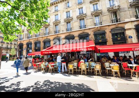 Parigini e turisti godono di bevande estive nel caffè Red Visor, marciapiede a Parigi Foto Stock