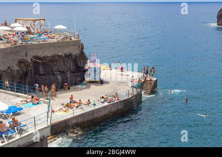 MADEIRA, PORTOGALLO - 28 LUGLIO 2018: I turisti prendere il sole e fare il bagno sulla spiaggia su un molo di cemento a Madeira, Portogallo. Foto Stock