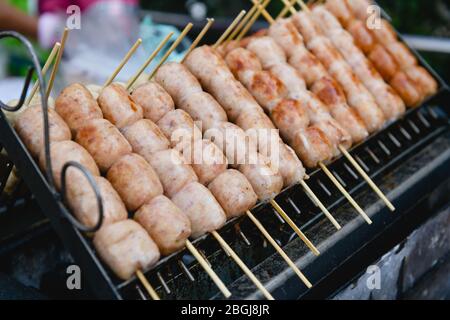 Carne di manzo alla griglia, pollo, agnello, fila di salsiccia di maiale su spiedini di legno, gustoso cibo di strada che vende al bancone di carne barbecue del mercato, bazar, festival Foto Stock