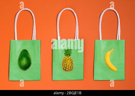 Tre sacchetti di carta con frutta, banana, ananas e icone avocado. Consegna di cibo da un negozio, caffè o ristorante Foto Stock