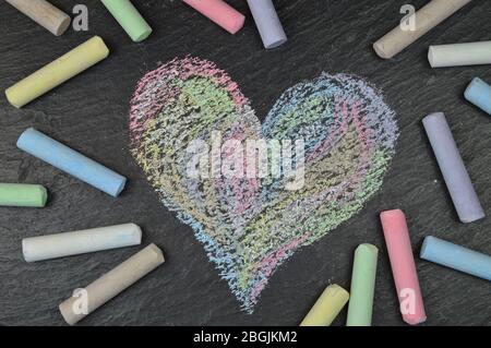 forma a cuore in gesso marciapiede su ardesia circondata da bastoni di gesso Foto Stock