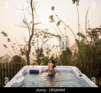 Donna che si gode un bagno in una vasca idromassaggio nelle Highlands dello Sri Lanka Foto Stock