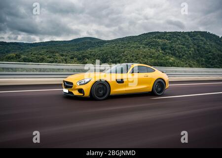 Colore giallo tecnologia moderna modello auto in autostrada sotto le nuvole Foto Stock