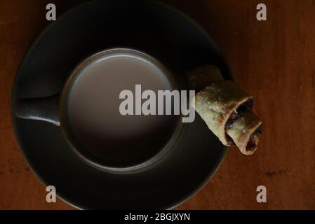 Una tazza di tè e un dolce di rugelach su un tavolo di legno Foto Stock