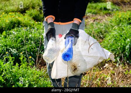 Volontari ecologici che puliscono il campo contaminato da bottiglie di plastica. Foto Stock