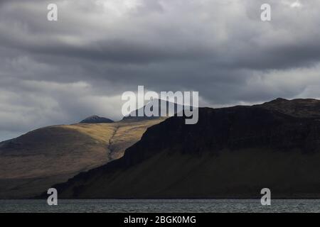 Vista di ben More, Isola di Mull, Scozia da Loch Na Keal in una giornata di bustery, nuvole sopra. Patch di luce del sole dietro scure Dunan Na Nighean scogliere. Foto Stock