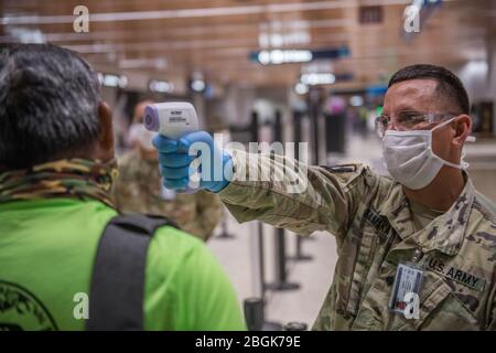 SPC. James Kamaka, 1° Squadron, 299° Cavalleria, Hawaii National Guard (HING) schermi in partenza passeggeri al Daniel K. Inouye International Airport, 6 aprile 2020, Honolulu, Hawaii. I soldati HING assistono il personale dei vigili del fuoco dell'aeroporto con lo screening del 100% dei viaggiatori che arrivano e partono, per includere i viaggi tra le isole. (STATI UNITI Foto della Guardia Nazionale dell'esercito di Sgt. John Schoebel) Foto Stock