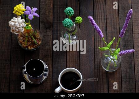 Incredibile tavolino con fiori fatti a mano e tazza di caffè su sfondo di legno, lavanda e daisy crochet per arredamento interno casa, creatività artistica Foto Stock