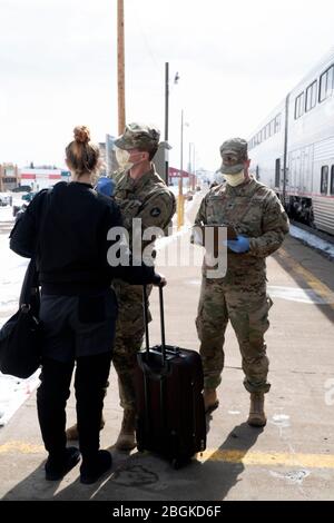 Esercito SPC. Trevor Dodson con il GSAB 1-189 da Shelby, Montana e Army SPC. Robert Swenson, con IL 1-163° TAXI di Conrad, Montana, esegue uno screening COVID-19 per un viaggiatore fuori stato alla stazione ferroviaria Amtrak di Shelby, Montana, 3 aprile 2020. 73 Montana Army e Air National Guard uomini e donne sono stati attivati per Stato attivo dovere da Steve Bullock governatore per lo schermo 17 posizioni in tutto lo stato nel tentativo di appiattire la curva in Montana. (STATI UNITI Foto della Guardia Nazionale aerea dello staff Sgt. Brandy Burke) Foto Stock