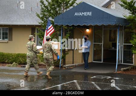 Guardia nazionale dell'esercito dell'Oregon Sgt. Krystle Marchell e Private di prima Classe Amaya Mullen consegnano le attrezzature di protezione personale (PPE) e le strutture di vita assistite nella zona di Portland, Oregon come parte della risposta COVID-19, 18 aprile 2020. Queste spedizioni di emergenza saranno consegnate dalla Guardia Nazionale dell'Oregon alle strutture di vita assistite in tutto lo stato che stanno vivendo gravi carenze. (Foto della Guardia Nazionale di John Hughel, Oregon Military Department Public Affairs) Foto Stock