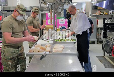 Alaska Army National Guard Soldiers Sgt. David Osmanson e il personale Sgt. Edward Jones, assegnato al Battaglione di reclutamento e conservazione AKARNG, lavora insieme ai dipendenti del Bean's Cafe, creando pranzi pre-confezionati in cucina al Bean's Cafe di Anchorage, Alaska, 8 aprile 2020. Questo cibo sarà distribuito a migliaia di locali Alaskans rifugio a Sullivan e Boeke arenas così come il programma di pranzo dopo la scuola Alaska. (STATI UNITI Foto della Guardia Nazionale dell'esercito di Sgt. Seth LaCount/rilasciato) Foto Stock