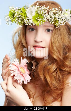 ritratto di bella ragazza giovane rossa sana in garland con farfalla su gerbera fiore su blu Foto Stock