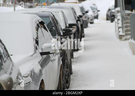 Auto su una strada della città in inverno coperta di neve. Foto Stock