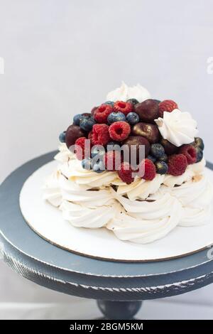 Torta Pavlova meringa con salsa al cioccolato, panna montata e ciliegie fresche, fragole, mirtilli. Foto Stock