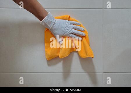 La mano in un guanto bianco con panno per pulire le piastrelle Foto Stock